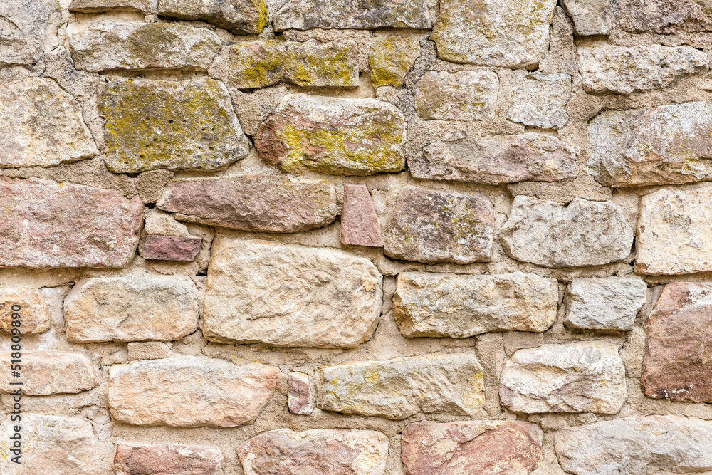 Fototapeta premium Wand oder Mauer aus Sandstein Ziegeln mit rissigen Fugen und Moos