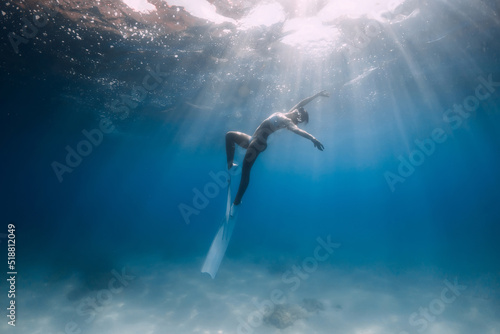 Freediver with white fins. Attractive woman posing underwater in blue sea