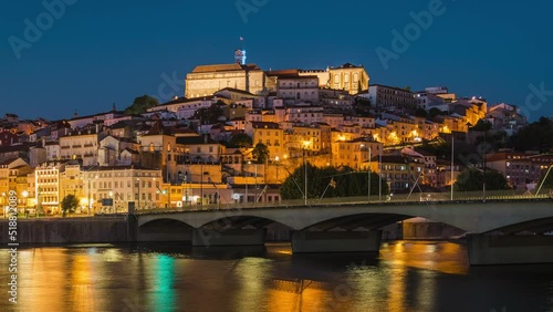 Day to night time lapse view of the historic old town of Coimbra seen from the Mondego River in Coimbra, Portugal, zoom in.  photo