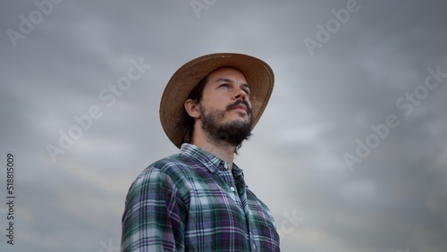 Obraz na płótnie Bearded man wearing plaid shirt holding spikelet, reed, dry grass his mouth and