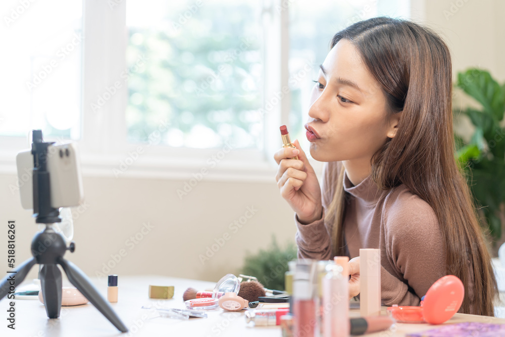 Beauty blogger, asian young woman vlogger makeup face, showing review lip stick cosmetics product while recording video, tutorial to share on social media. Business online influencer on smartphone. Beauty blogger, asian young woman vlogger makeup face, showing review lip stick cosmetics product while recording video, tutorial to share on social media. Business online influencer on smartphone.