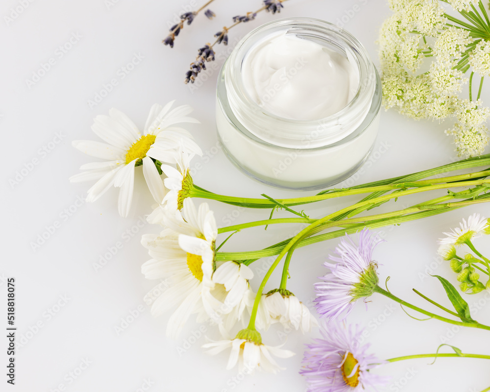 Organic cream and wild flowers on a white background. Concept of wild-harvested beauty and natural cosmetics based on a wild plant. Soft focus style