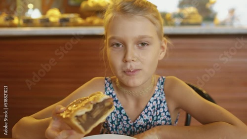 Close-up of cute happy little girl eating a piece of apple pie in a cafe.
