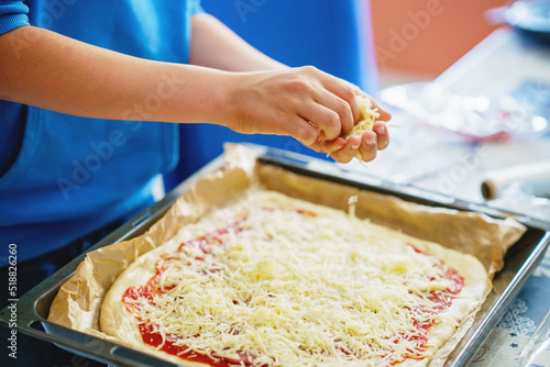Kid make pizza for dinner, hands add cheese. Healthy food for family lunch. Boy helping.