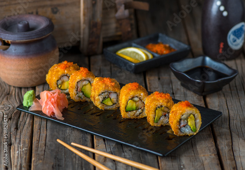 Φωτογραφία CRUNCHY CALIFORNIA sushi roll served in a cutting board isolated on wooden backg