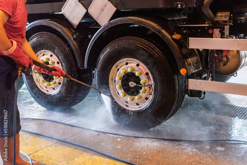 Operator of a truck wash cleaning the tires with pressurized water.