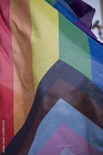 Close Up rainbow gay pride flag outside on a street. Symbol of the Lesbian Bisexual Transgender LGBT community waving in wind against cloudy sky. Social movement for freedom and equliaty. Copy Space