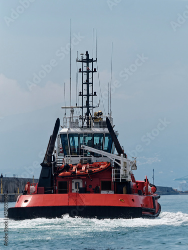 Back  view of a Powerful Tugboat moving fast next to breakwater to the ship to be towed