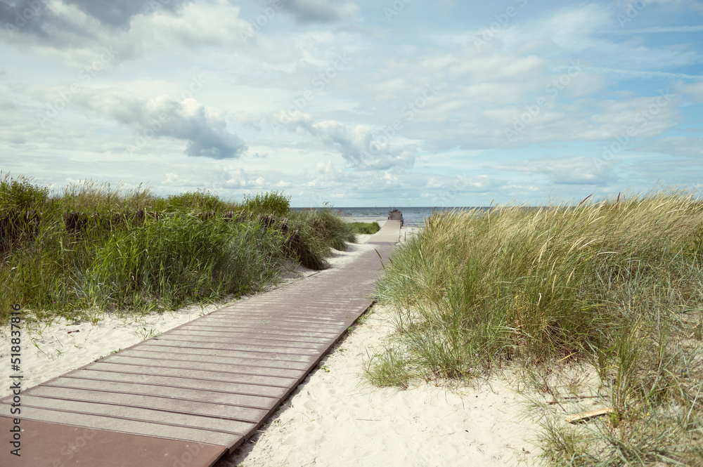 Pathway at white beach with green dune grass at Baltic sea in north Germany