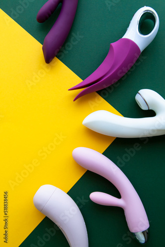 Collection of different types of sex toys on a green and yellow background. 