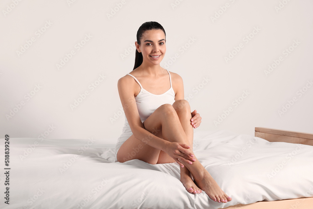 Young woman with beautiful smooth legs sitting on bed at home Young woman with beautiful smooth legs sitting on bed at home
