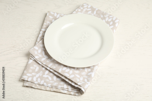 Empty plate and napkin on white wooden table