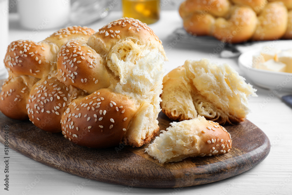 Homemade braided bread with sesame seeds on white wooden table, closeup. Traditional challah