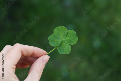 Woman holding one beautiful green clover leaf outdoors, closeup © New Africa