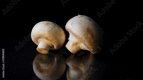 Champignons on a black background. Frame. Two mushrooms isolated on black reflective background.