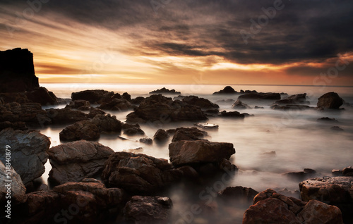 O'Sullivans Beach shoreline with clouds over sea at sunset.