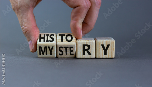 History versus mystery symbol. Concept words History and mystery on wooden cubes. Businessman hand. Beautiful grey table grey background. Business, History versus mystery concept. Copy space.