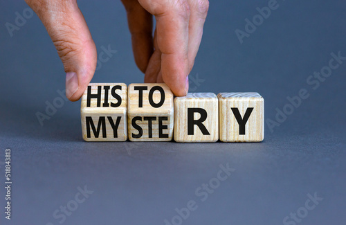 History versus mystery symbol. Concept words History and mystery on wooden cubes. Businessman hand. Beautiful grey table grey background. Business, History versus mystery concept. Copy space.
