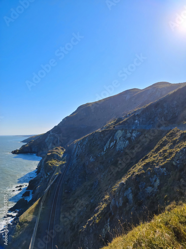 Aerial view of mountain road near blue sea, sandy beach at sunset in summer. Oludeniz, Turkey. Top view of road, trees, clear water, mountain. Beautiful landscape with highway, rocks and sea coast