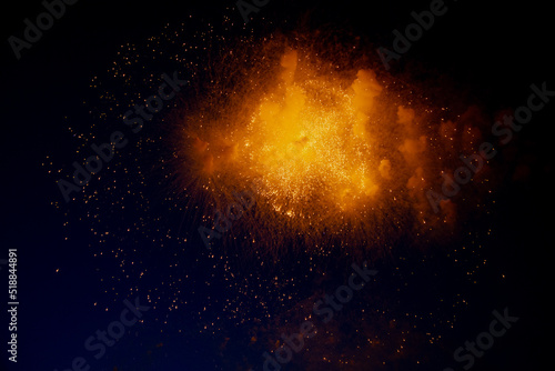Bright orange glowing fireworks with sparks flying sideways against the night sky. High quality photo