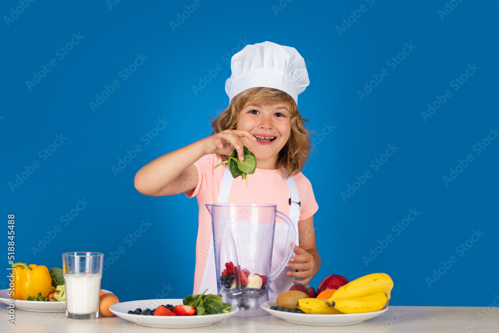 Child chef isolated on blue. Funny little kid chef cook wearing uniform cook cap and apron cooked food with spinach in the kitchen. Child chef isolated on blue. Funny little kid chef cook wearing uniform cook cap and apron cooked food with spinach in the kitchen.