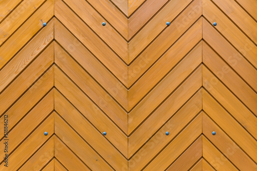 Bretter aus Holz iIm Fischgrätenmuster als Wand oder Tür angeordnet