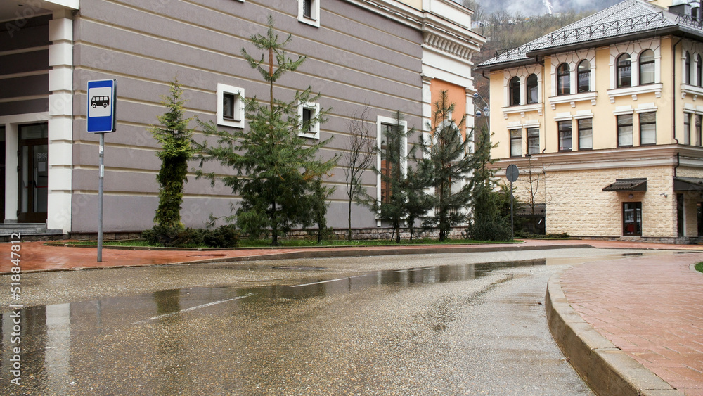 Wet road along a city street against the background of historical architecture and snowy mountain peak. Stock footage. European landscape of a small town, road, and beautiful buildings.