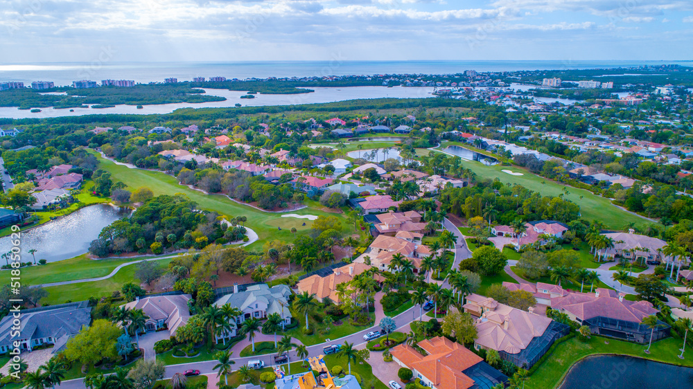 Aerial of Golf Course Community in Naples, Florida with Drones Eye View of Real Estate in the Foreground and The Bay with Mangroves and the Gulf of Mexico