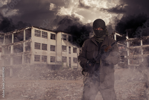 armed masked soldier in front of destroyed building. guerrilla warfare concept. photo