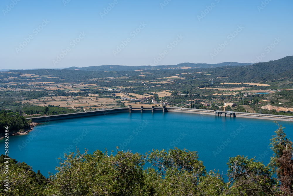 Large blue reservoir and distant El Grado Dam, Hydro-Electricity Generation, Huesca, Spain, a concrete hydro-electric reservoir dam, clear blue sky