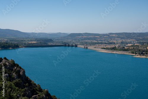 Large blue reservoir and distant El Grado Dam, Hydro-Electricity Generation, Huesca, Spain, a concrete hydro-electric reservoir dam, clear blue sky
