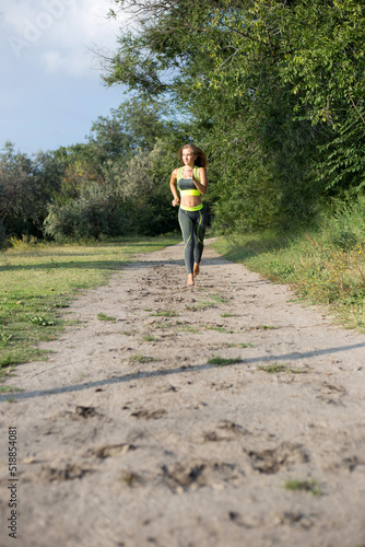 Young blonde girl runs barefoot in the forest. Running woman, front view. Jogging in the park