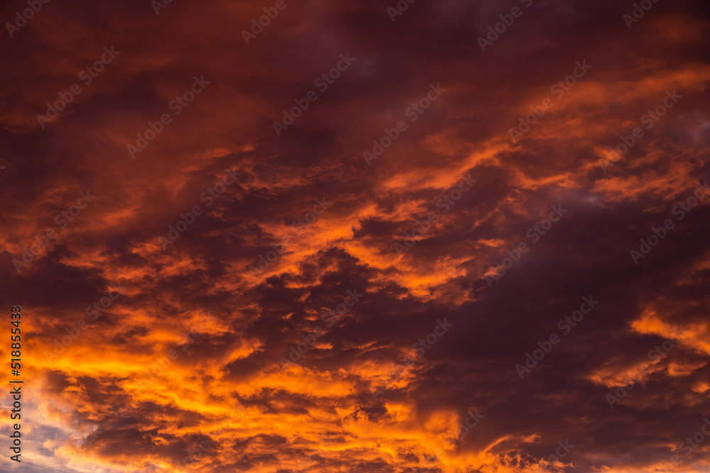 Epic Dramatic bright sunrise, sunset orange yellow red sky with storm clouds in sunlight abstract background texture