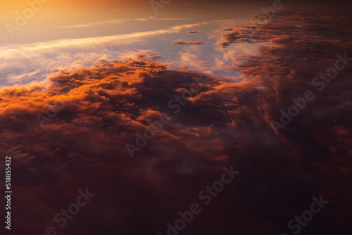 Epic dramatic sunrise above planet earth, storm sky with dark cloud, orange yellow sun and sunlight. Sunset view with thunderstorm from space over clouds