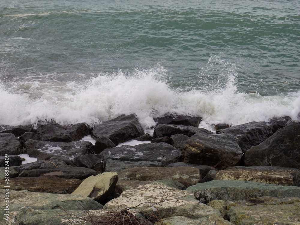 Rocky seashore. The shore is fortified with huge stones. Large waves on the pier.  Big wave. Windy weather