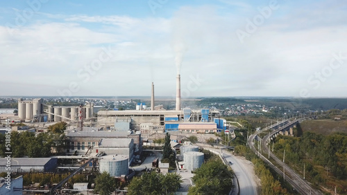 Aerial view of power plant generating heat and electricity on blue cloudy sky background. Stock footage. Visible high pipes with smoke, industrial landscape. photo