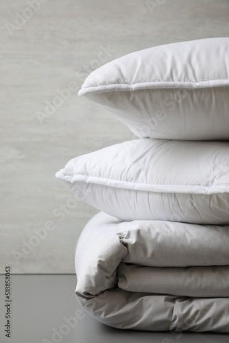 Soft folded blanket and pillows on light grey table, closeup
