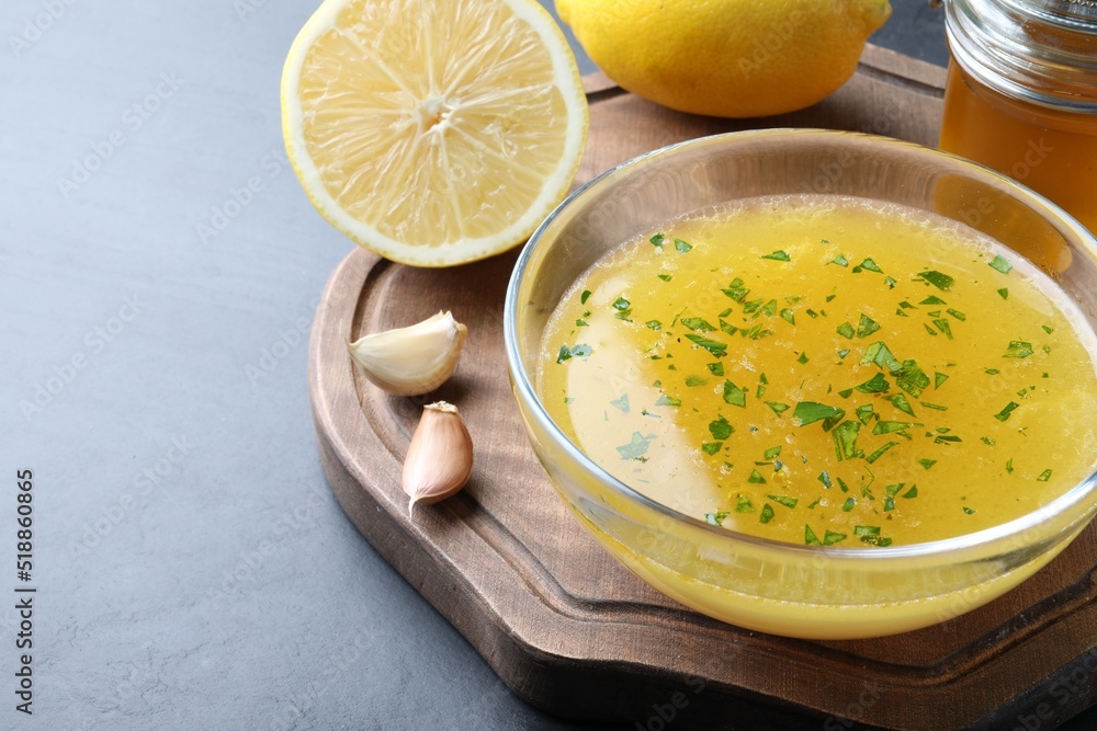 Bowl with lemon sauce and ingredients on dark table, space for text. Delicious salad dressing Bowl with lemon sauce and ingredients on dark table, space for text. Delicious salad dressing