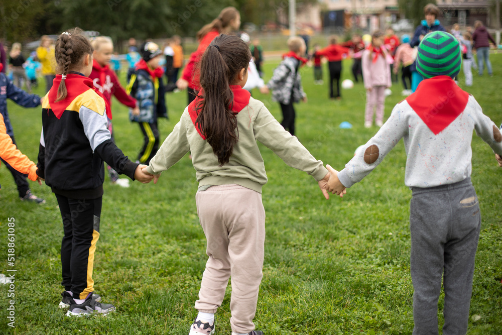 Children hold hands forming circle. Children at festival in summer. Schoolchildren study in nature. Children hold hands forming circle. Children at festival in summer. Schoolchildren study in nature.