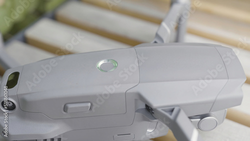 Close up of quadrocopter or drone details. Action. Professional shooting equipment, grey quadcopter body with glowing indicator ready for flight.
