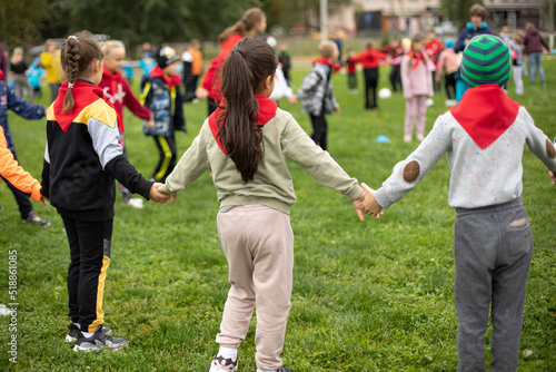 Children hold hands forming circle. Children at festival in summer. Schoolchildren study in nature.