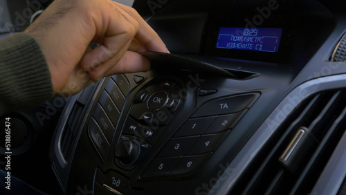 Man's hand puts the disk into the car player. Button control for compact disk player in a car. Hand puts the disk into the radio car