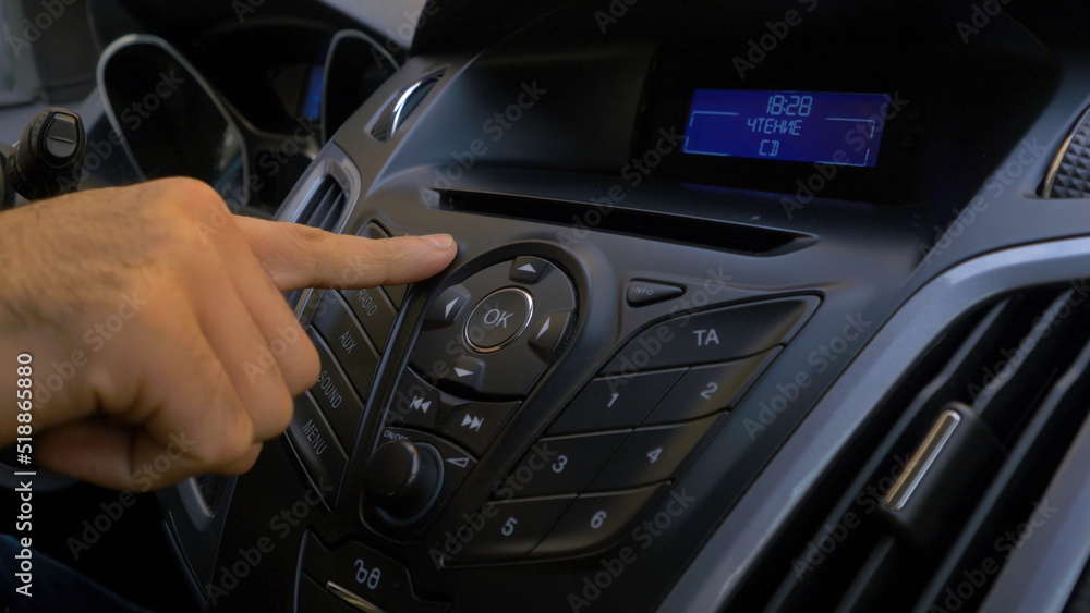 Man's hand puts the disk into the car player. Button control for compact disk player in a car. Hand puts the disk into the radio car