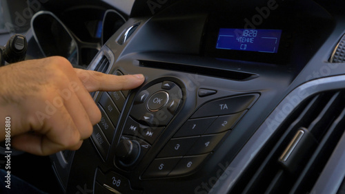 Man's hand puts the disk into the car player. Button control for compact disk player in a car. Hand puts the disk into the radio car © Media Whale Stock