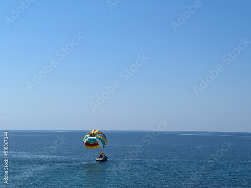 Boat with a colored parachute floats on the sea against a blue sky