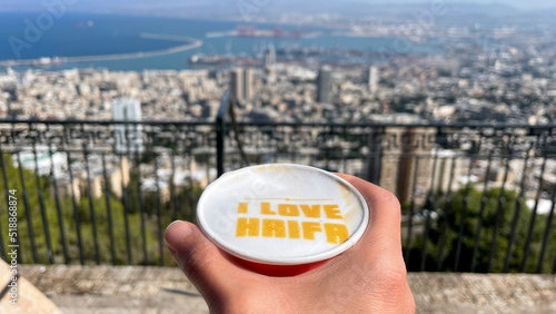 The caption I LOVE HAIFA in a cup of coffee and a view of Haifa city in the background. photo