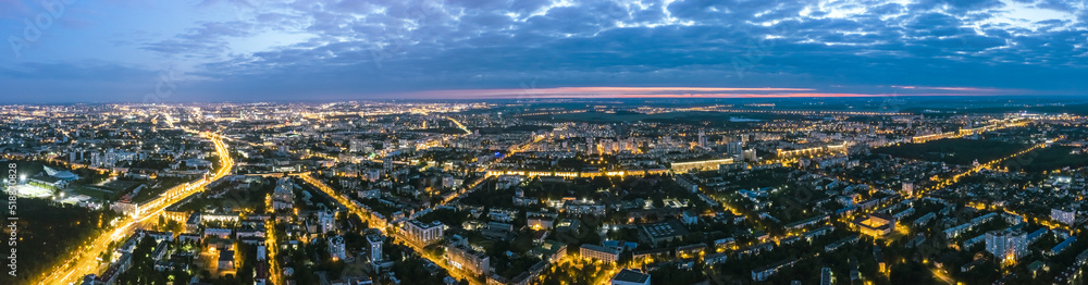 panoramic view of illuminated city streets and buildings after sunset. aerial view from flying drone.