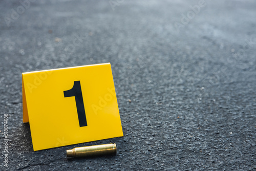 One yellow crime scene evidence marker on the street after a gun shooting brass bullet shell casing rifle