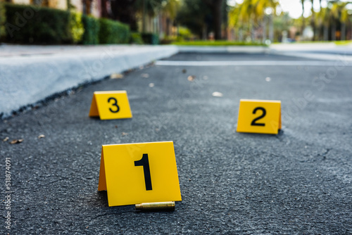 A group of yellow crime scene evidence markers on the street after a gun shooting brass bullet shell casing rifle photo