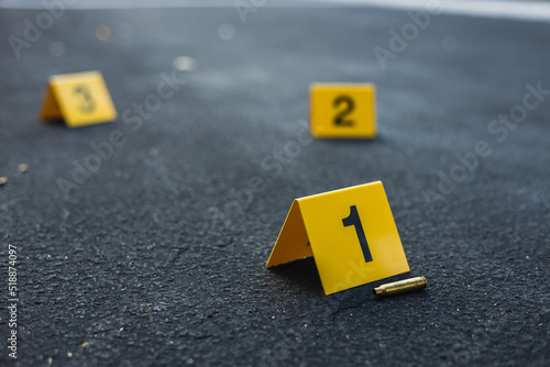 Fotografija A group of yellow crime scene evidence markers on the street after a gun shootin